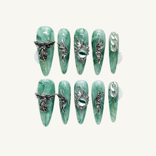 A set of stiletto press-on nails with a jade green marble pattern, adorned with vintage silver angel, wing, chain, and dragon eye charms.