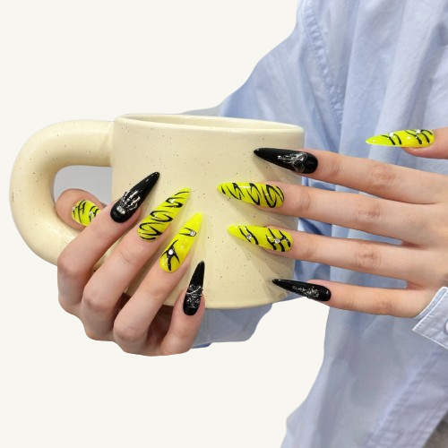 A set of goth punk press-on nails with neon green and black graffiti, rhinestones, and 3D metallic skull charms on black nails.
