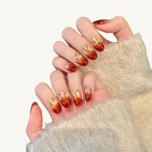 An amber-textured handmade press-on set with a gold-to-orange-red glitter cat-eye gradient.