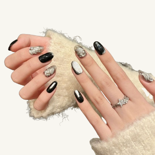 A set of handmade oval press-on nails featuring hand-painted white feathers, pearls, and a mix of black and silver glitter.
