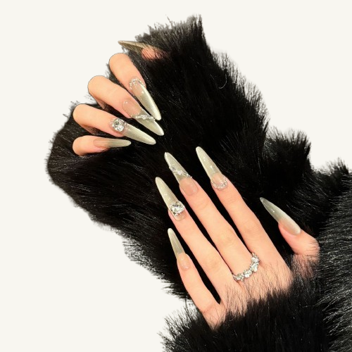 A set of handmade stiletto press-on nails, champagne gold cat-eye, inlaid with large, clear crystals in various cuts.