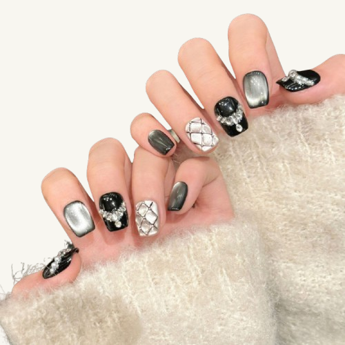 A set of classic style press-on nails, featuring white quilting, black nails with pearl and diamond jewelry, and a silver cat eye.