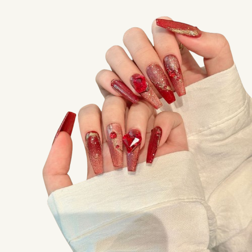 A handmade red-themed long coffin press-on nail set with a cat-eye effect, adorned with red gems, a heart crystal, and golden curves.