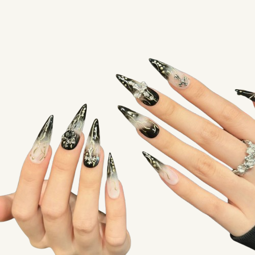 Hand wearing handmade XL stiletto nails with black and white smoke ombre, adorned with 3D crosses and metallic charms.