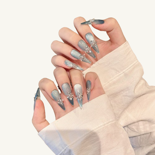 A geode-style set of handmade oval press-on nails, light blue and clear design with shell and gold foil inside, outlined with gold lines.