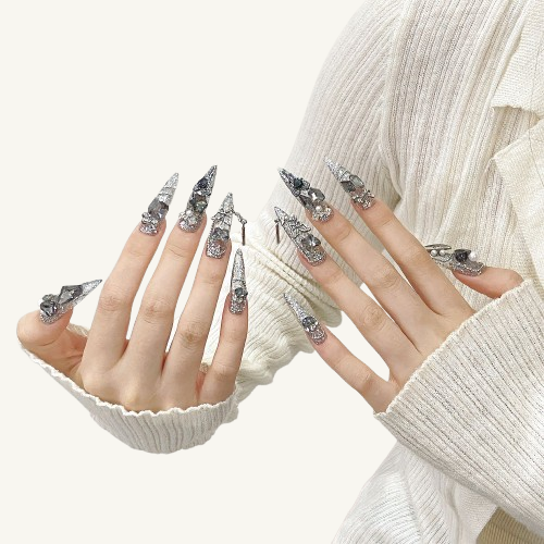A set of dark elf themed XL stiletto nails, handmade with large grey crystals and 3D metal butterfly charms.