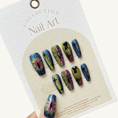 A set of gothic chameleon cat eye press-on nails with hand-painted dragon's eye and star designs on long coffin-shaped fake nails.