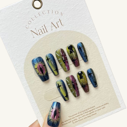 A set of gothic chameleon cat eye press-on nails with hand-painted dragon's eye and star designs on long coffin-shaped fake nails.