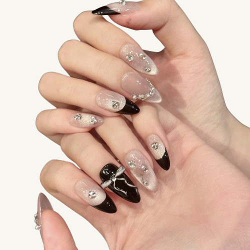 An elegant set of French handmade press-on nails with a silvery-white cat-eye, black tips, adorned with rhinestones, pearls, and a silver bow.
