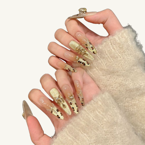 A French-style handmade stiletto press-on set, nude gradient base, with a gold leopard French tip inlaid with champagne crystals and chains.