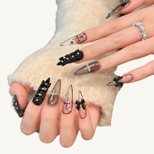 A set of long stiletto gothic press-on nails in a black and white theme, adorned with 3D bows, crosses, chains, and rhinestones.