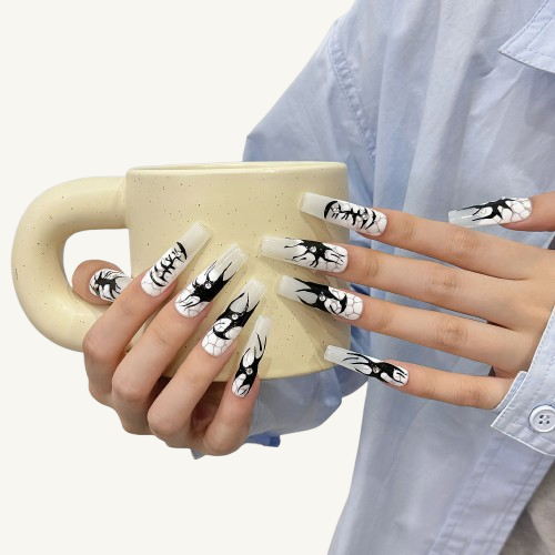 A set of long square press-on nails with black  graffiti art over an icy grey-white base, accented with sparkling crystals.