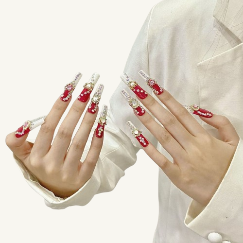 A set of Valentine's Day themed long coffin nails, handmade in red and white with pink heart gems, pearls, and many rhinestones.