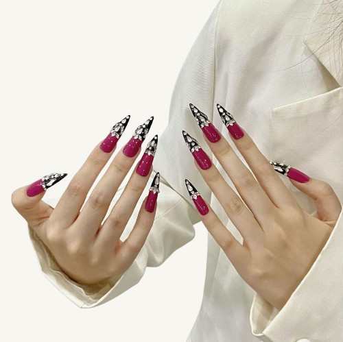 A set of luxurious hot pink and black color-block press-on nails, with long coffin tips heavily embellished with crystals and diamonds
