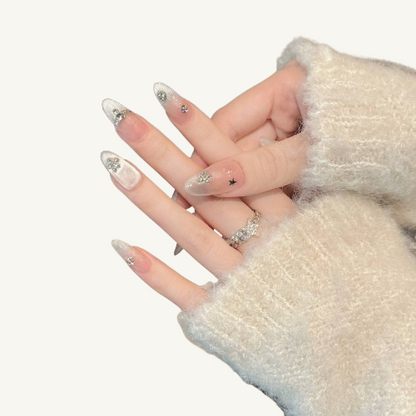 Hands wearing long almond press-on nails with a silver cat eye effect and ice crystal snowflake designs.