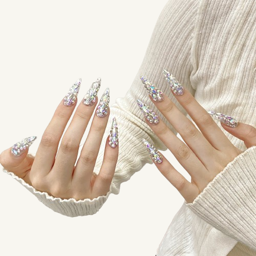 A pair of hands wearing XXL stiletto press-on nails, with the nails covered in ice-crystal-like aurora rhinestones.