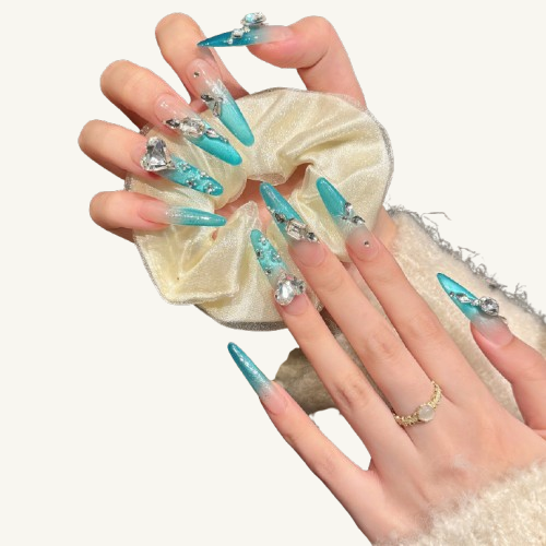 A set of long almond press-on nails with an icy teal cat-eye ombre, inlaid with large, fancy-cut diamonds including a heart shape.
