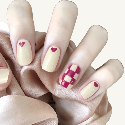 A love-themed set of short oval press-on nails, featuring creamy yellow and hot pink, with patterns of little hearts and a checkerboard.