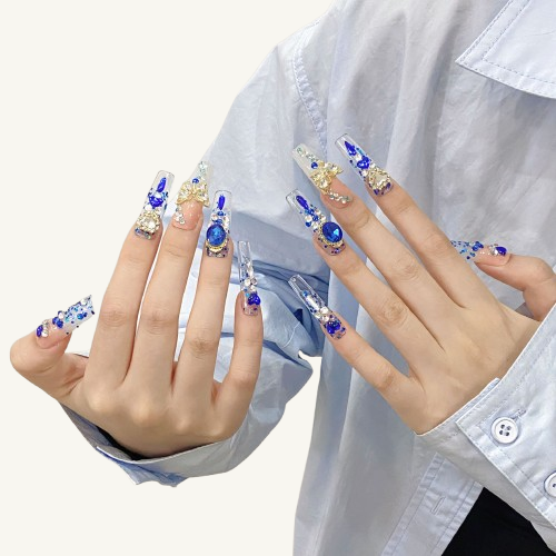 A set of Y2K princess style long square press-on nails, featuring a 3D butterfly, royal blue gems, and a pearl heart frame.
