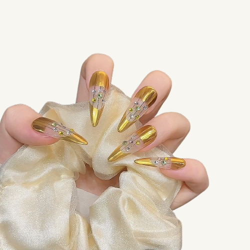 A set of long stiletto press-on nails in mirror gold, featuring a creative cutout design with vertical black lines and colorful rhinestones.