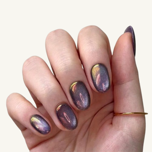 A set of short oval press-on nails with a purple and gold chameleon cat-eye effect, resembling a nebula in space.