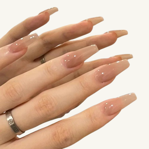 Two hands wearing long  ballerina press-on nails with a nude ombre jelly finish and small white dot details.