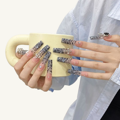 A set of Y2K style long square press-on nails with an ombre tiger print background, adorned with a Baroque cross and 3D star charms