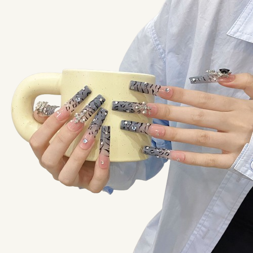 A set of Y2K style long square press-on nails with an ombre tiger print background, adorned with a Baroque cross and 3D star charms