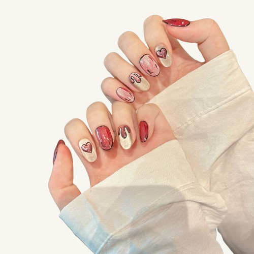 A graffiti-style set of handmade press-on nails, pink and white cat-eye base with black hand-drawn lines, hearts, and drips.