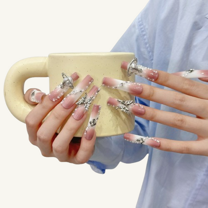 A set of XXL square press-on nails with a milk-tea-to-white gradient, adorned with a silver Saturn ring, a full-diamond bow, and abundant pearls and rhinestones.