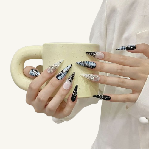 A set of punk style long stiletto press-on nails in a black and white theme, featuring 3D embossed silver beads and a Baroque cross.