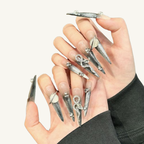 A set of long stiletto press-on nails in a silver glitter ombre design, adorned with large 3D snake and planet metallic charms.