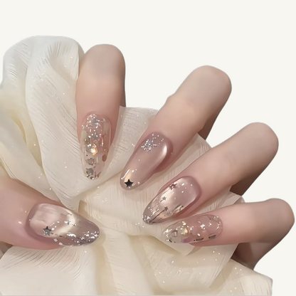 A set of soft shimmer glitter oval press-on nails with 3D silver stars and gold & silver foil flakes.