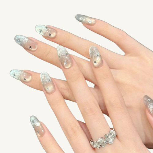 A set of handmade champagne gold to silver gradient cat-eye press-on nails with silver star decorations and thread details, oval shape.