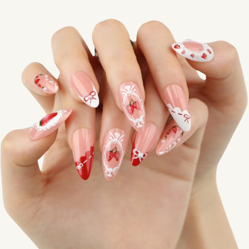 A hand wearing a set of medium almond press-on nails with hand-painted strawberries, white lace frames, and pearl embellishments.