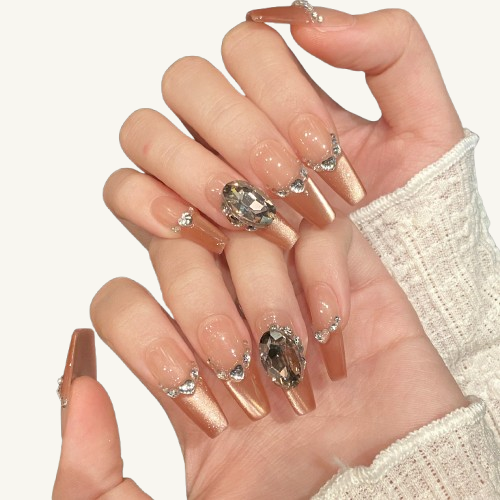 A sunset-themed handmade press-on set, rose gold cat-eye French tips, adorned with crystals, pearls, and an oval smoky quartz.