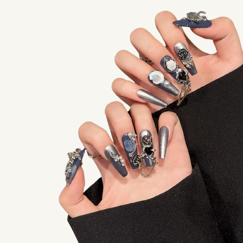 A set of vintage-style press-on nails in hazy blue and silver glitter, with cameo gems, roses, and connecting chains.