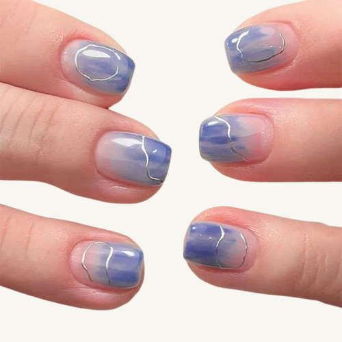 Two hands displaying short square press-on nails with a blue and pink watercolor design and a thin silver line.